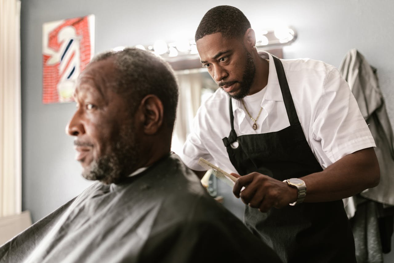 A focused barber performs a haircut on an elderly client in a contemporary barbershop setting.
