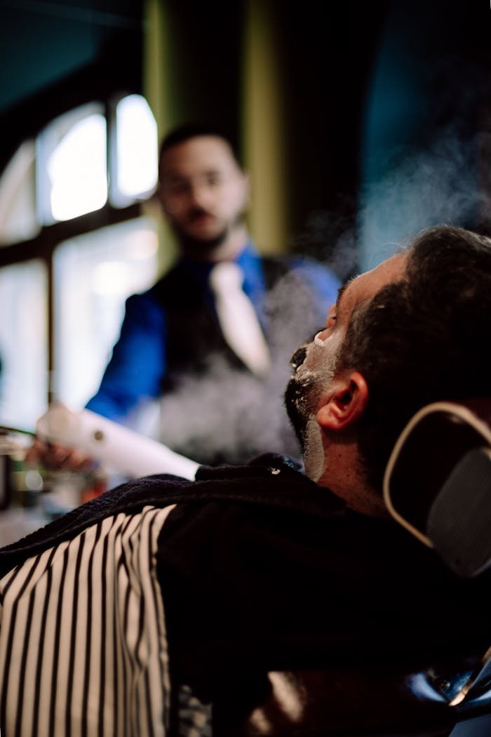 A client receives a traditional shave at a barber shop in Geneva, Switzerland, showcasing expert grooming services.