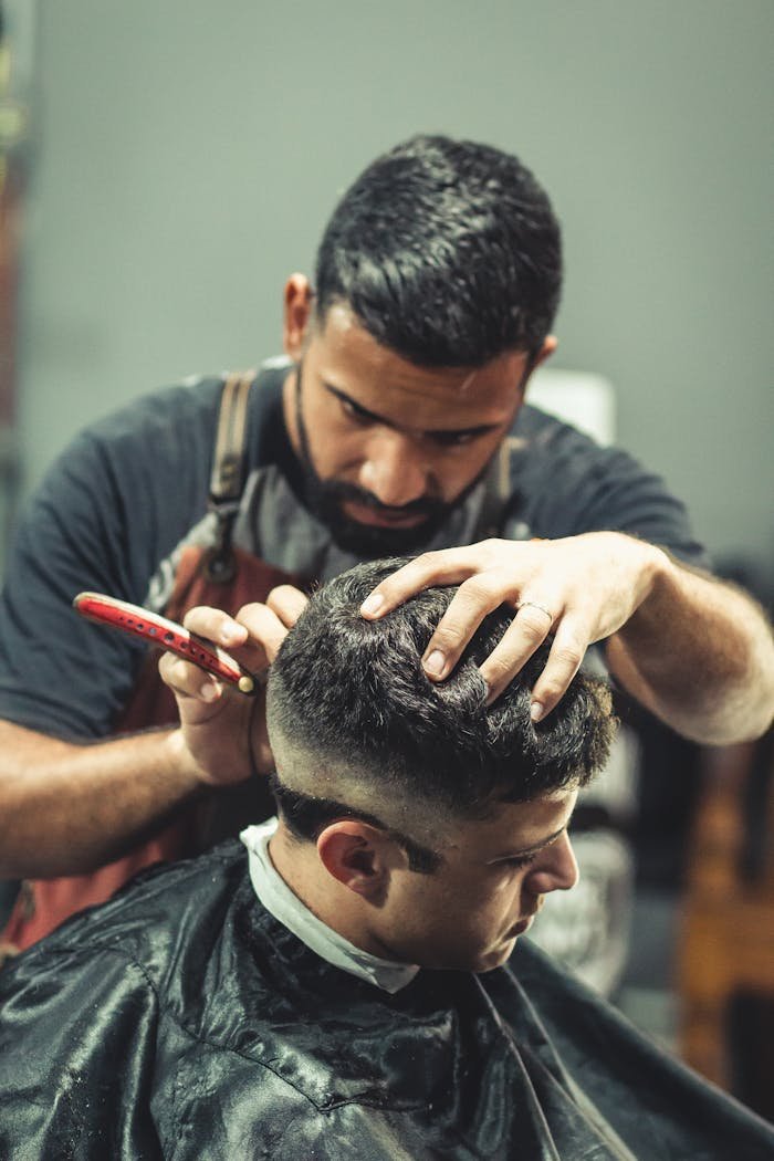A professional barber expertly cutting a mans hair in a stylish barbershop setting.