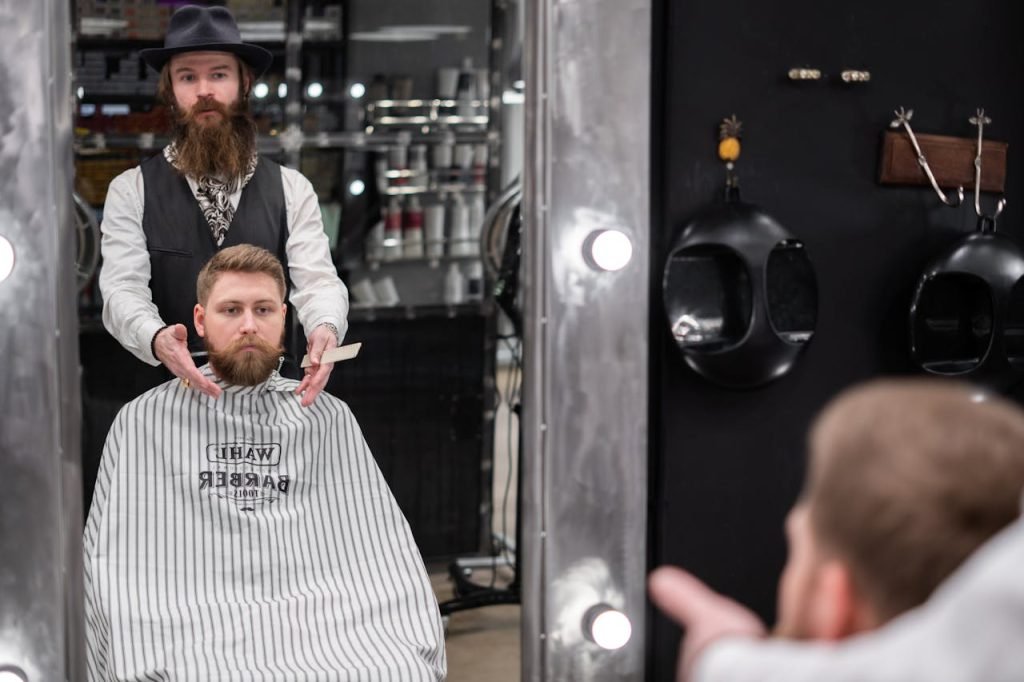 A bearded barber grooming a clients beard in a contemporary barbershop.